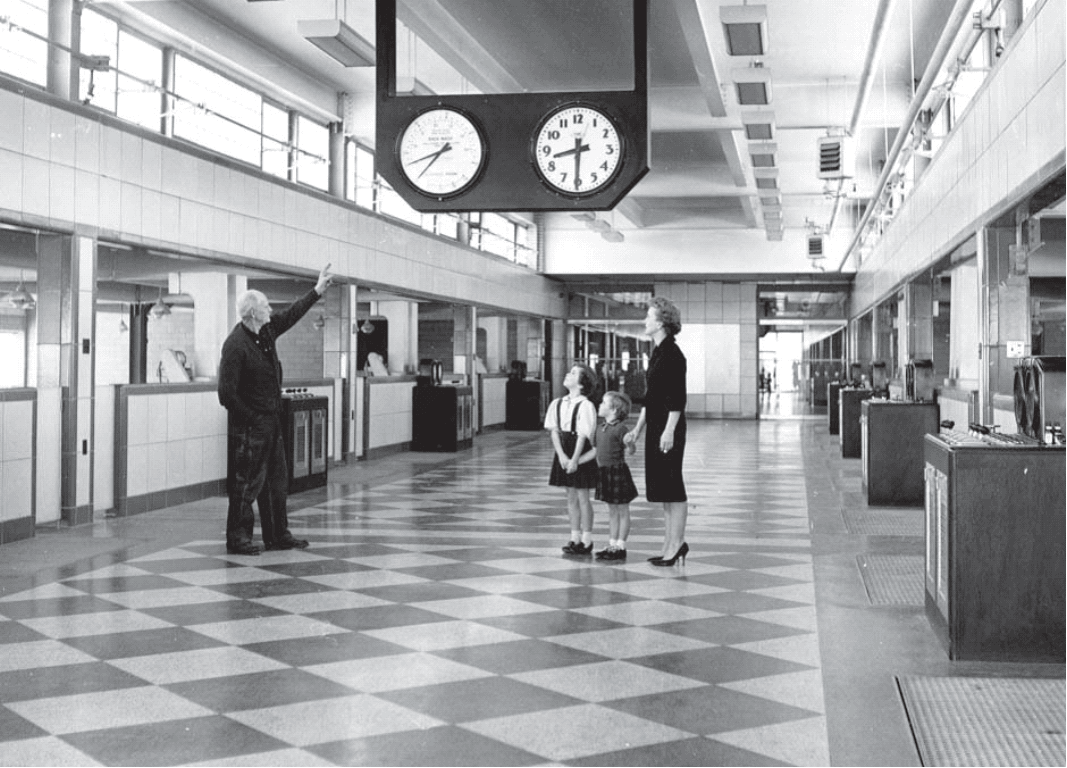 Historic Photo of a Water Treatment Employee Gesturing to a Meter During a Tour