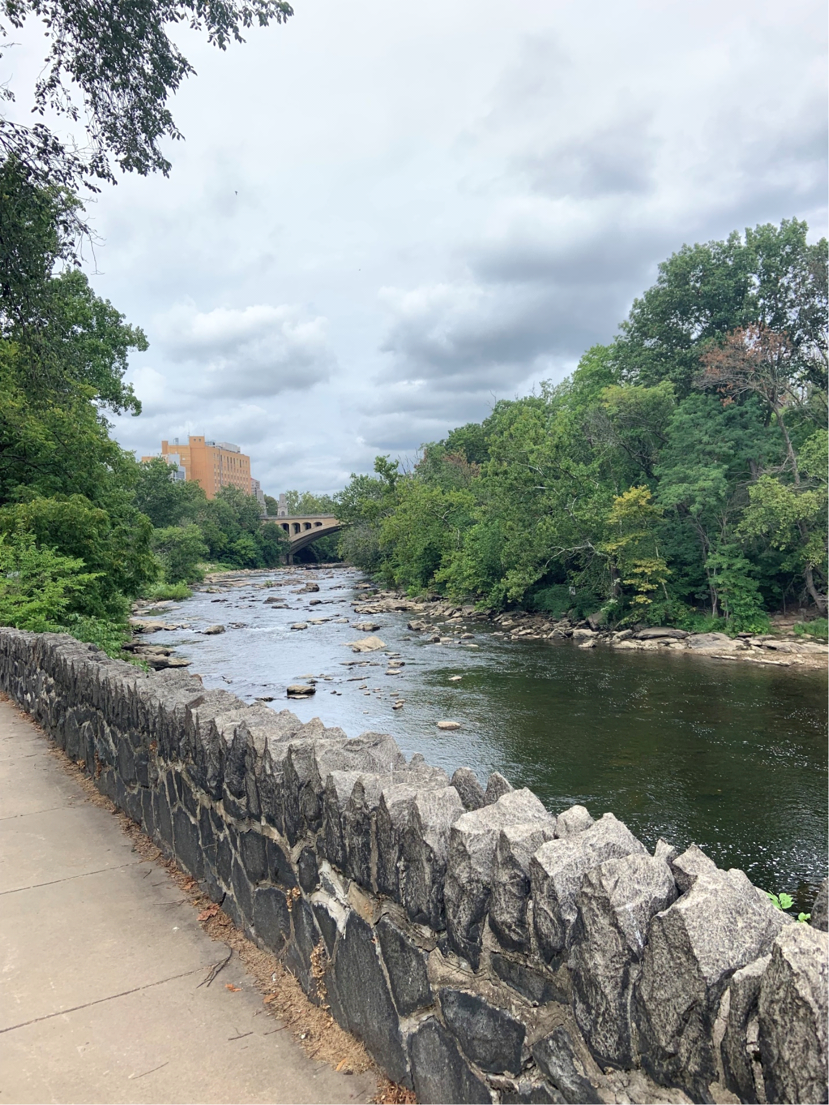 Concrete and Stone Bridge Spanning over a River near an Urban Area